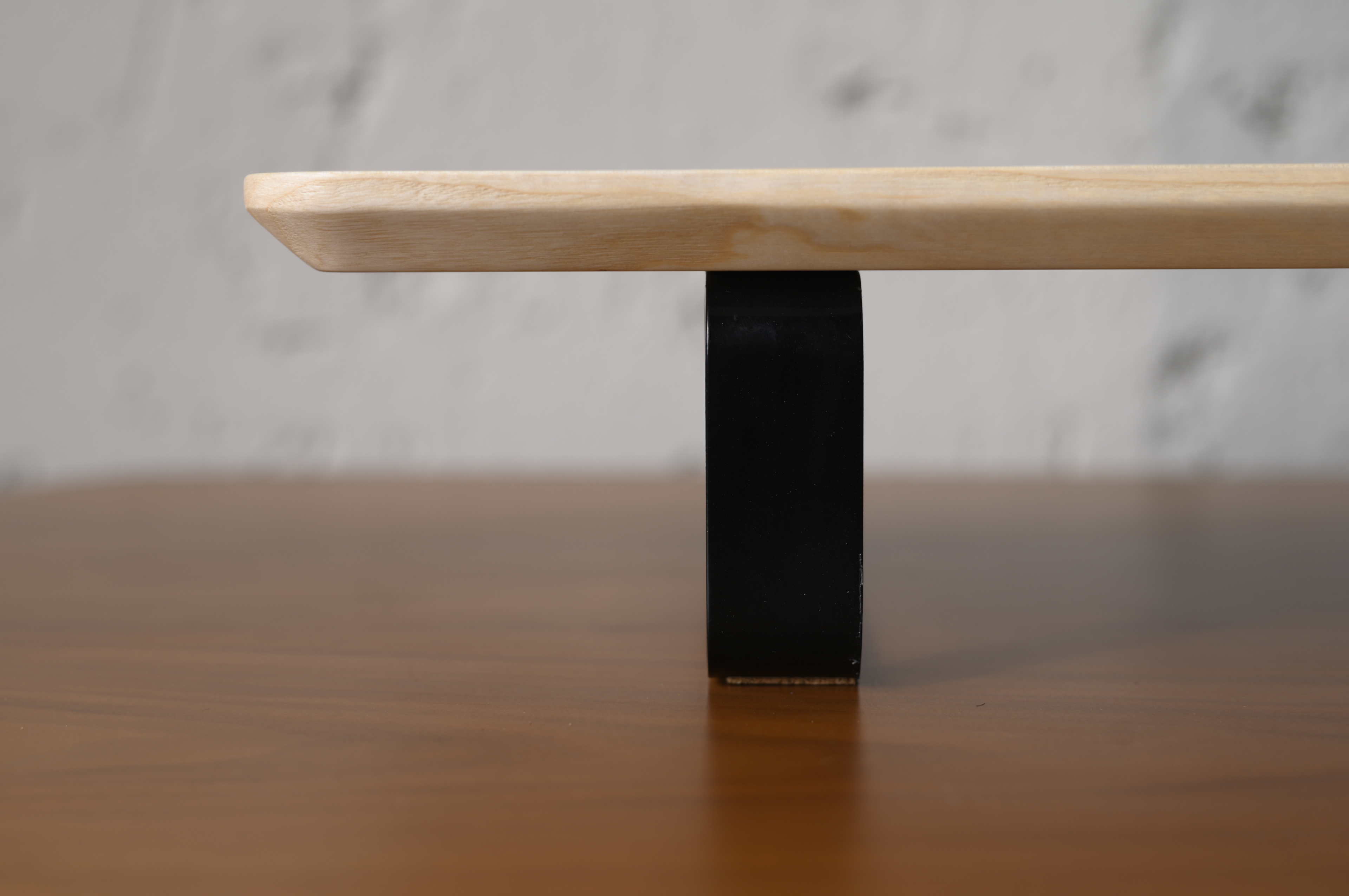 Wooden table with a black square base on a wooden surface
